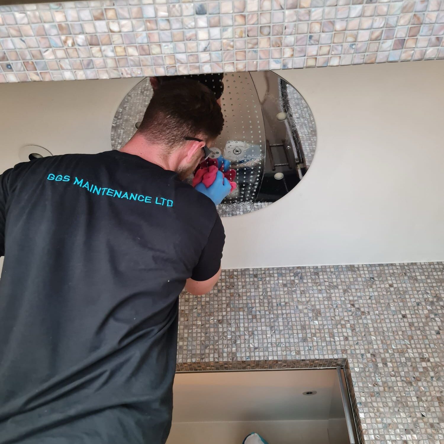 A technician fixes a circular ceiling light.